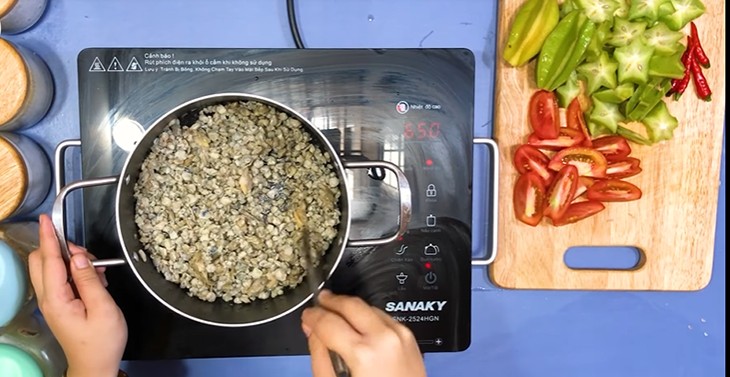 Đang xào thịt hến và cà chua để tăng hương vị cho canh khế