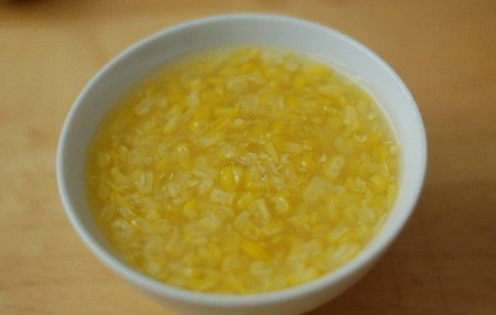 Món chè ngô thành phẩm được trình bày hấp dẫn trong bát thủy tinh, với màu vàng óng và cốt dừa trắng muốt