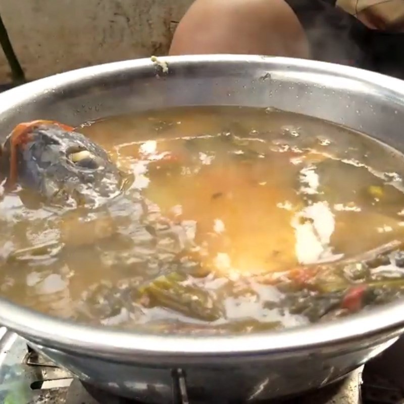 Cho rau ngót vào nồi canh cá rô đang sôi