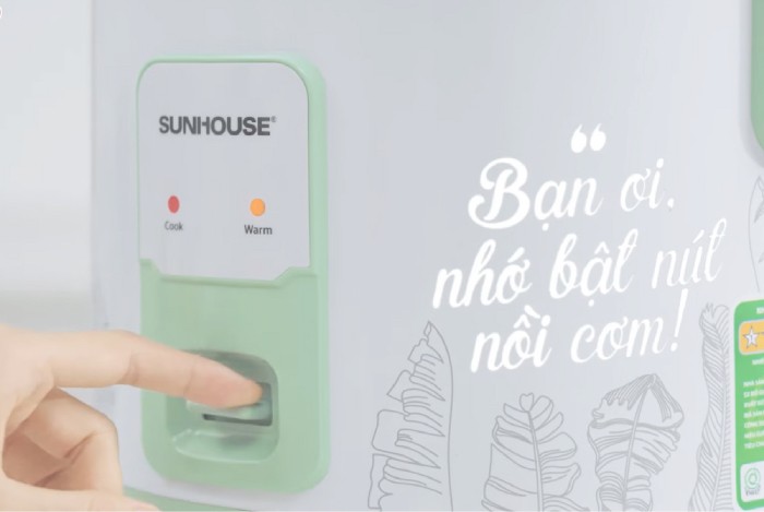 Người dùng bấm nút trên nồi cơm điện cơ để bắt đầu nấu cháo gạo lứt