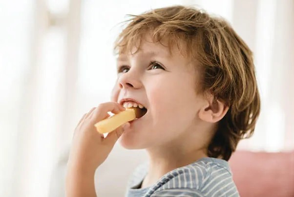 Bé vui vẻ thưởng thức món ăn, minh họa lợi ích dinh dưỡng từ phô mai Con Bò Cười trong cách nấu cháo phô mai con bò cười cho bé.
