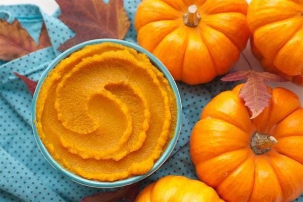 Bát bột bí đỏ màu vàng cam mịn màng cho bé ăn dặm, có hình mặt cười trang trí.