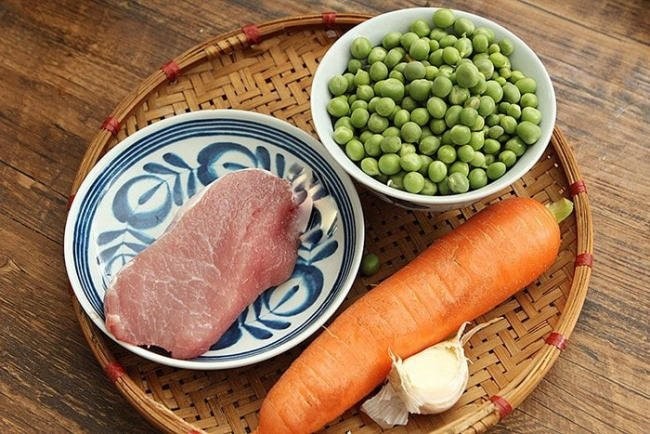 Bát bột đậu Hà Lan và cà rốt màu vàng cam nhạt, kèm theo một chiếc thìa nhỏ.