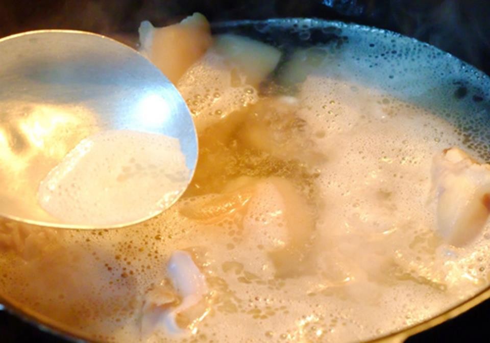 Nồi xương hầm đang sôi, bọt được hớt sạch để nước dùng trong vắt khi nấu canh măng miến
