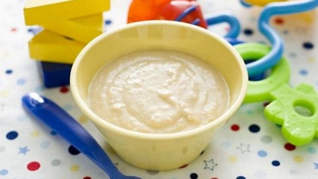 Bát bột gạo ăn dặm màu trắng mịn màng cho bé, kèm theo thìa nhỏ.