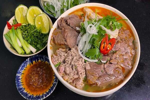 Món bún bò tái Huế thành phẩm với thịt bò mềm ngọt, sợi bún dai và các loại rau ăn kèm tươi xanh, thể hiện kết quả cuối cùng của cách nấu bún bò tái