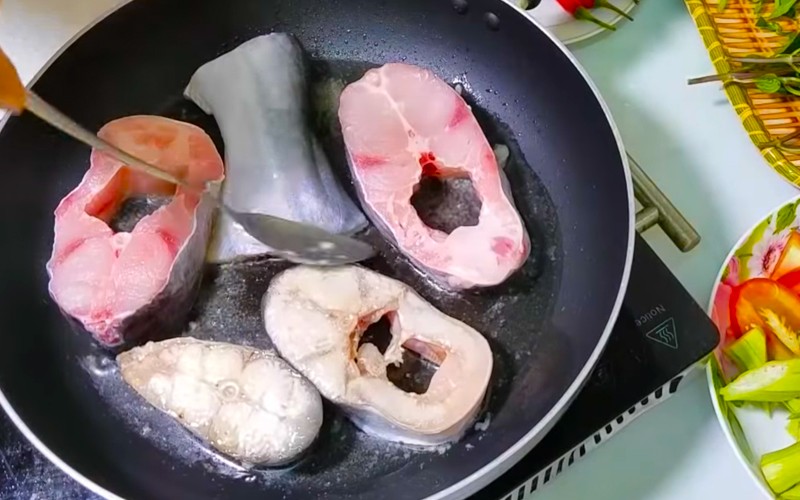 Những miếng cá tra được chiên sơ vàng đều các mặt, sẵn sàng cho vào nồi canh