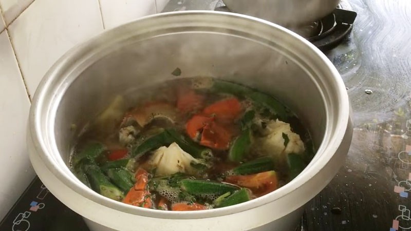 Nồi canh chua cua biển đã hoàn thành với cà chua, đậu bắp, và ngò ôm tươi xanh