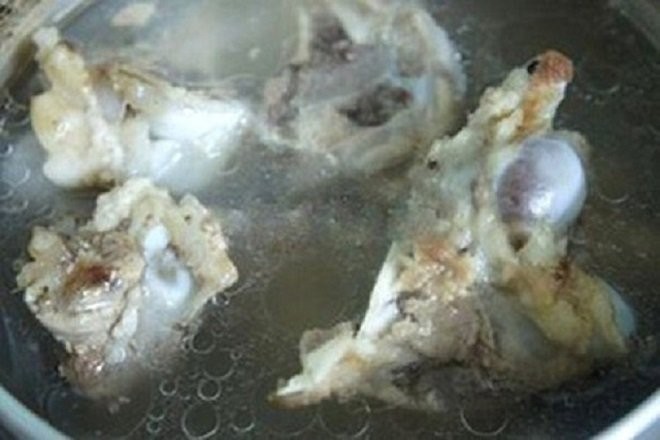 Nồi nước hầm xương đang sôi, cần vớt bọt để nước dùng cháo thịt băm tía tô trong.