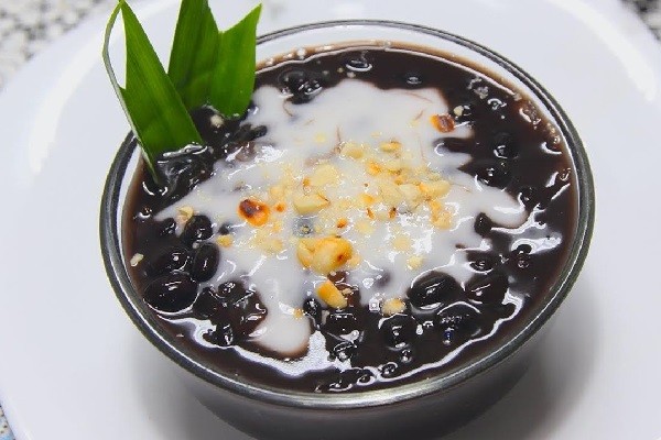 Bát chè đậu đen nước cốt dừa béo ngậy, hấp dẫn, rắc dừa bào sợi và đậu phộng rang.