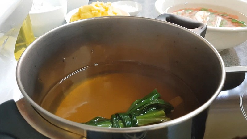 Nồi nước đường nâu và lá dứa đang sôi nhẹ, chuẩn bị cho món chè đậu xanh bột lọc