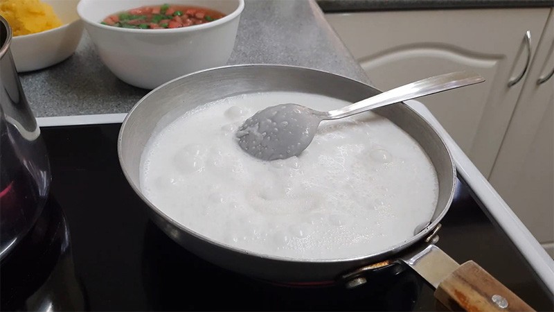Nồi nước cốt dừa sánh mịn đang được đun nhỏ lửa, tạo độ béo ngậy cho chè đậu xanh bột lọc