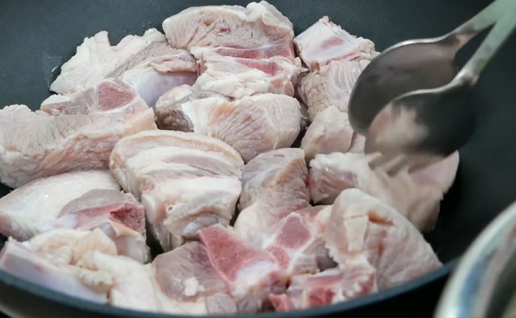 Chiên sơ sườn heo trên chảo nóng để tăng hương vị và màu sắc cho món hủ tiếu sườn kho