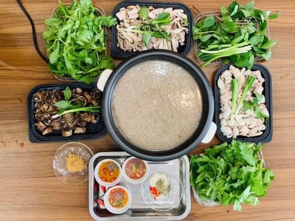 Bát lẩu cháo thập cẩm với tôm, thịt và rau ăn kèm