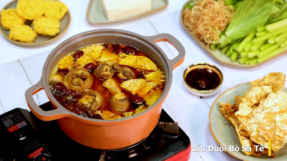 Nồi lẩu đuôi bò sa tế thơm lừng, hấp dẫn đã sẵn sàng để thưởng thức cùng các loại rau sống và mì trứng, mang đến bữa ăn ấm cúng và tròn vị.