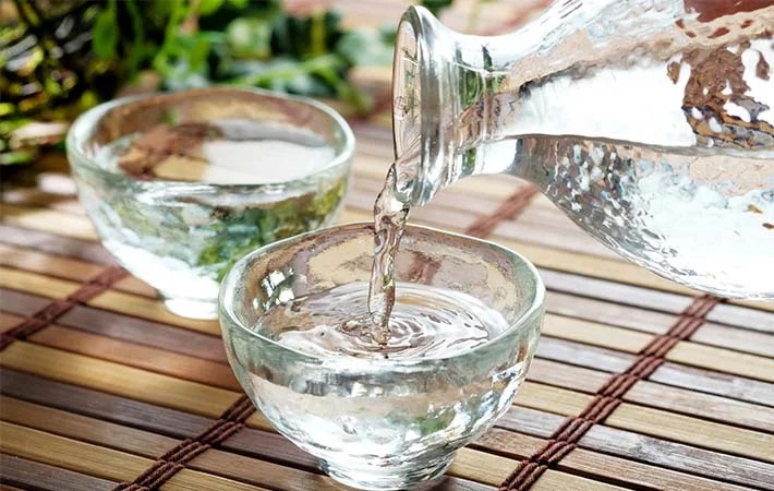 Dòng rượu trong vắt chảy ra từ vòi ngưng tụ, thành quả của một quy trình chưng cất tỉ mỉ, tượng trưng cho cách nấu rượu ngon nhất