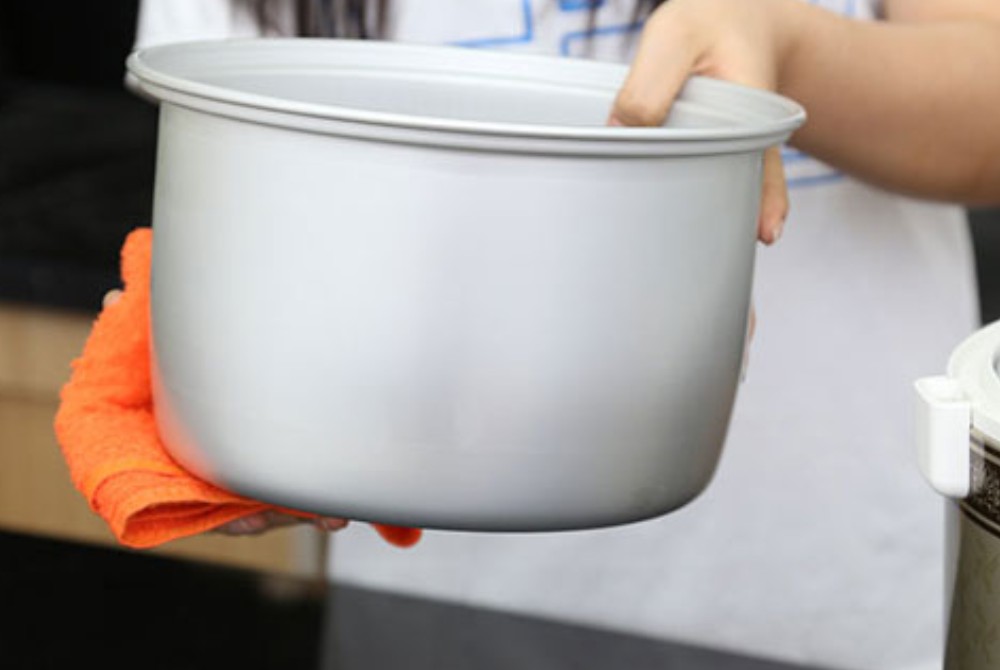 Đáy và mặt ngoài lòng nồi cơm điện được lau khô ráo, đảm bảo an toàn và hiệu quả khi nấu xôi khoai môn.