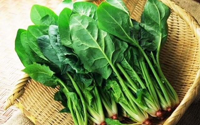 Món ăn dặm cải bó xôi và khoai mỡ màu xanh nhạt trong bát, cùng một chiếc thìa nhỏ.