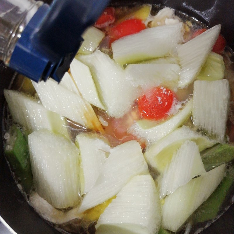 Thêm các loại rau vào nồi canh chua lườn cá hồi