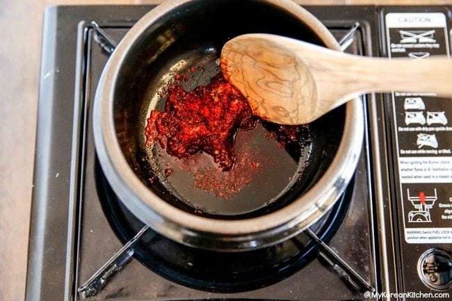 Phi thơm dầu ớt, bột ớt gochugaru và tỏi băm để tạo màu sắc và hương vị đặc trưng cho món canh