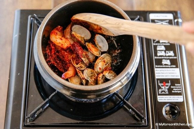 Xào nhanh tôm và nghêu với hỗn hợp gia vị cay, chuẩn bị cho nồi canh đậu hũ non Hàn Quốc