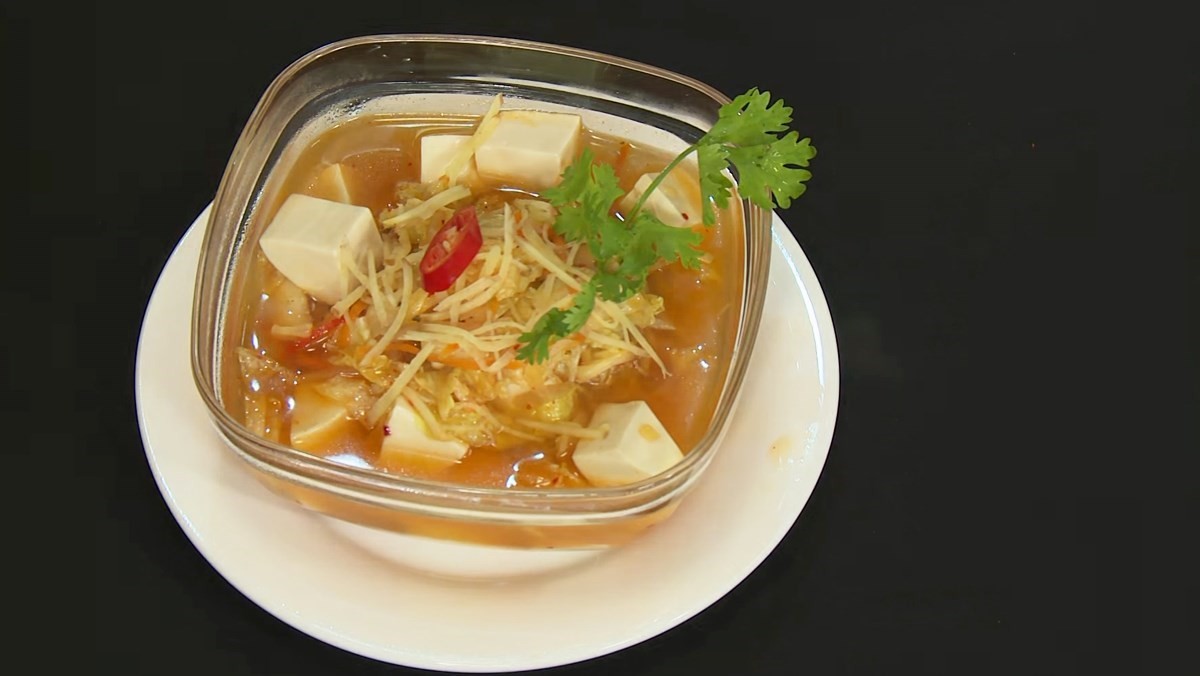 Thành phẩm canh kim chi đậu phụ chay, miếng đậu trắng mềm nổi bật trong nước canh đỏ cam.