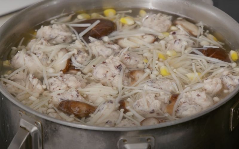 Nồi canh nấm kim châm đang sôi với mọc và rau củ