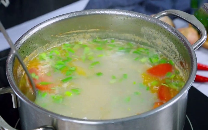 Nồi canh trai rau răm đang sôi nhẹ, chuẩn bị cho hành lá, rau răm và ớt vào để hoàn thiện hương vị