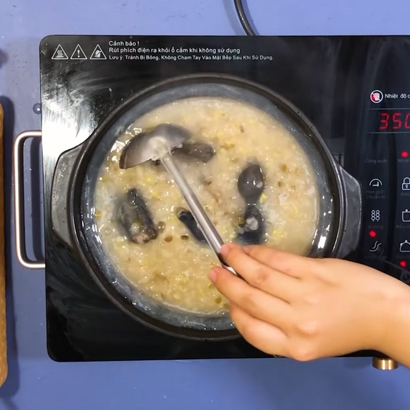 Nồi cháo gà ác đậu xanh đang sôi nhẹ, chuẩn bị hoàn thành