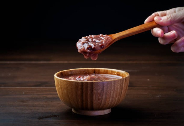Bát cháo gạo lứt thành phẩm thơm ngon, mềm dẻo, được trang trí với hành lá và rau thơm