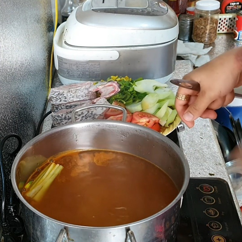 Cho cá chẽm vào nồi canh đang sôi