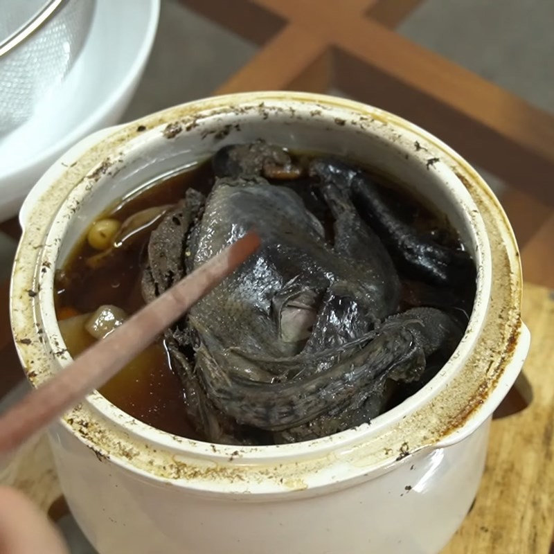Lọc nước hầm gà ác qua rây, loại bỏ bã thuốc cho cháo bé