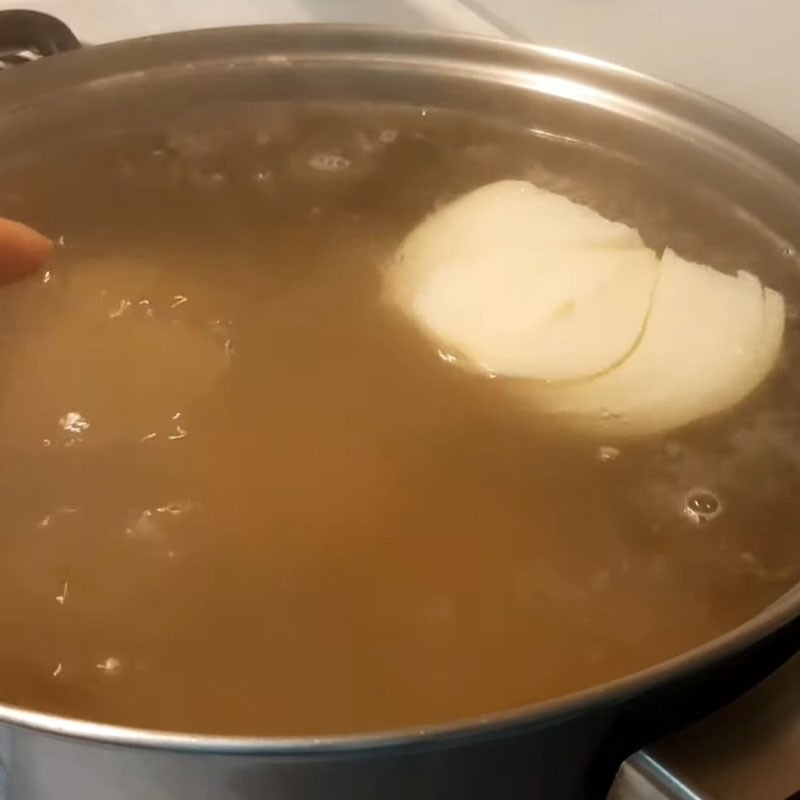 Thêm hành tây và tôm khô vào nồi nước hầm bánh canh cua giò heo