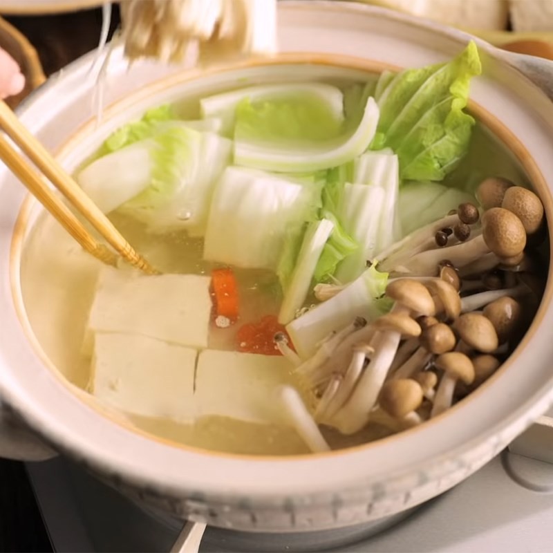 Sắp xếp các loại rau củ và nấm vào nồi nước dùng Dashi đang sôi