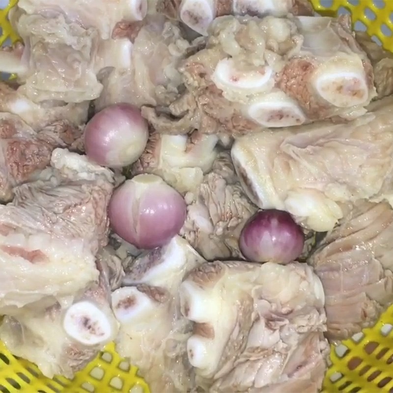 Nồi sườn bò đang được hầm cùng hành tím, nước dùng trong và ngọt.