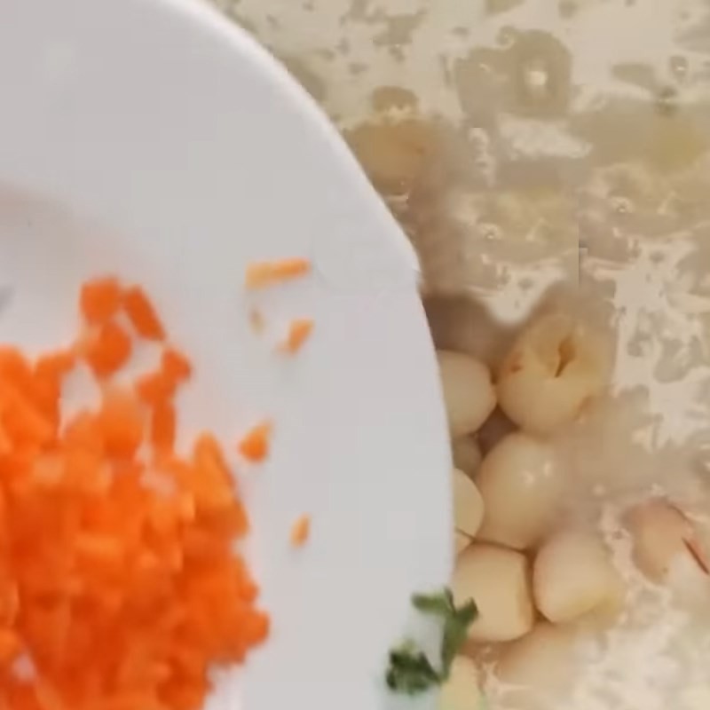 Đang khuấy đều nồi cháo gà hạt sen trên bếp, đảm bảo cháo không bị dính đáy và tất cả các nguyên liệu chín đều.