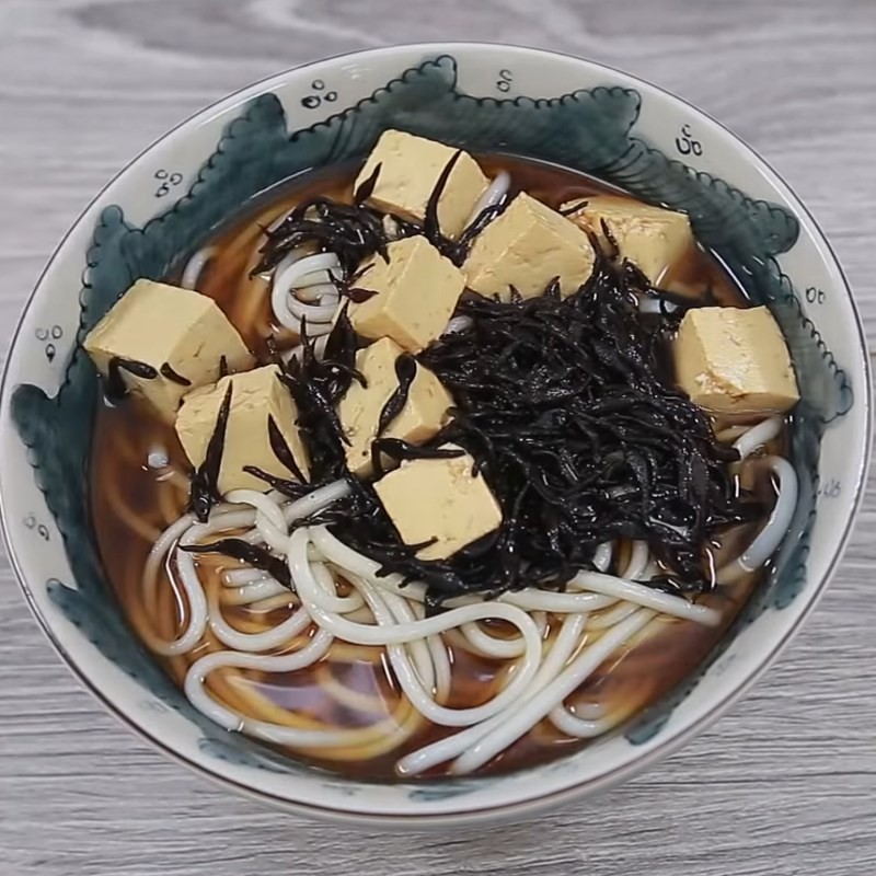 Nước dùng dashi nóng hổi được chan vào tô mì Udon