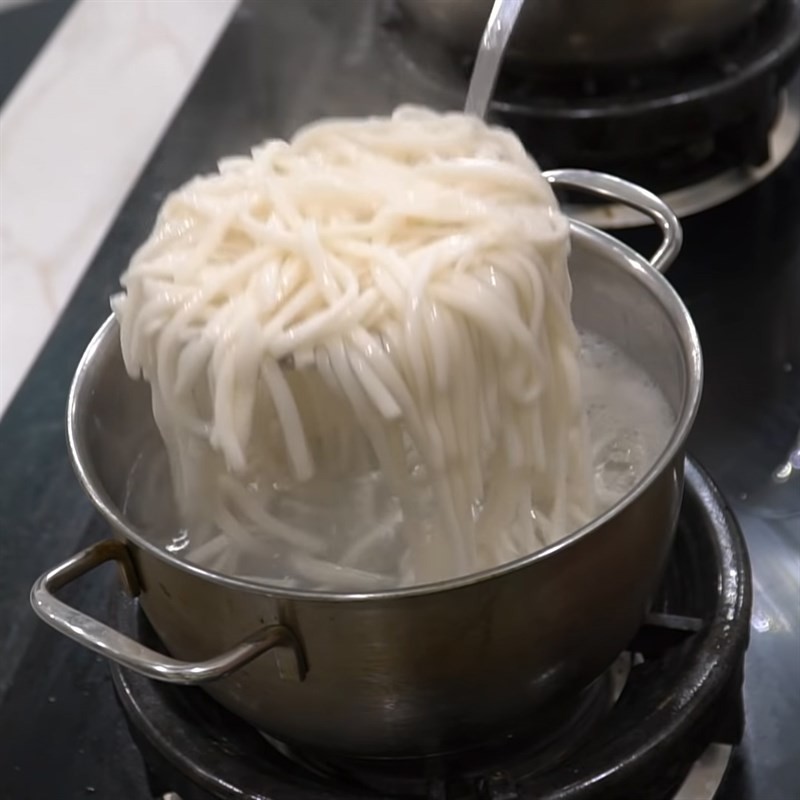 Cho sợi bánh canh và cá lóc xào vào tô, chan nước lèo nóng hổi