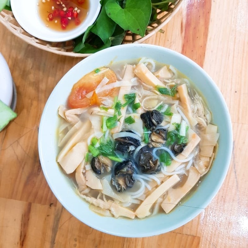 Bày bún tươi ra tô, chan nước dùng bún ốc măng nóng hổi cùng thịt ốc, măng và hành lá thái nhỏ, sẵn sàng thưởng thức.
