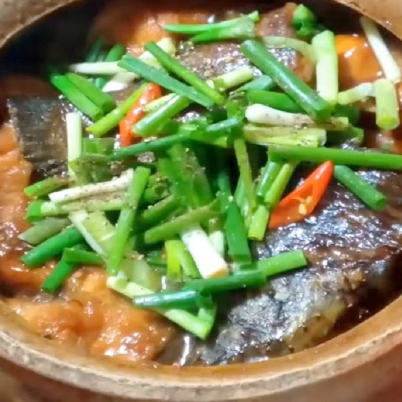 Thêm hành lá và tiêu vào nồi cá lóc kho me trước khi tắt bếp