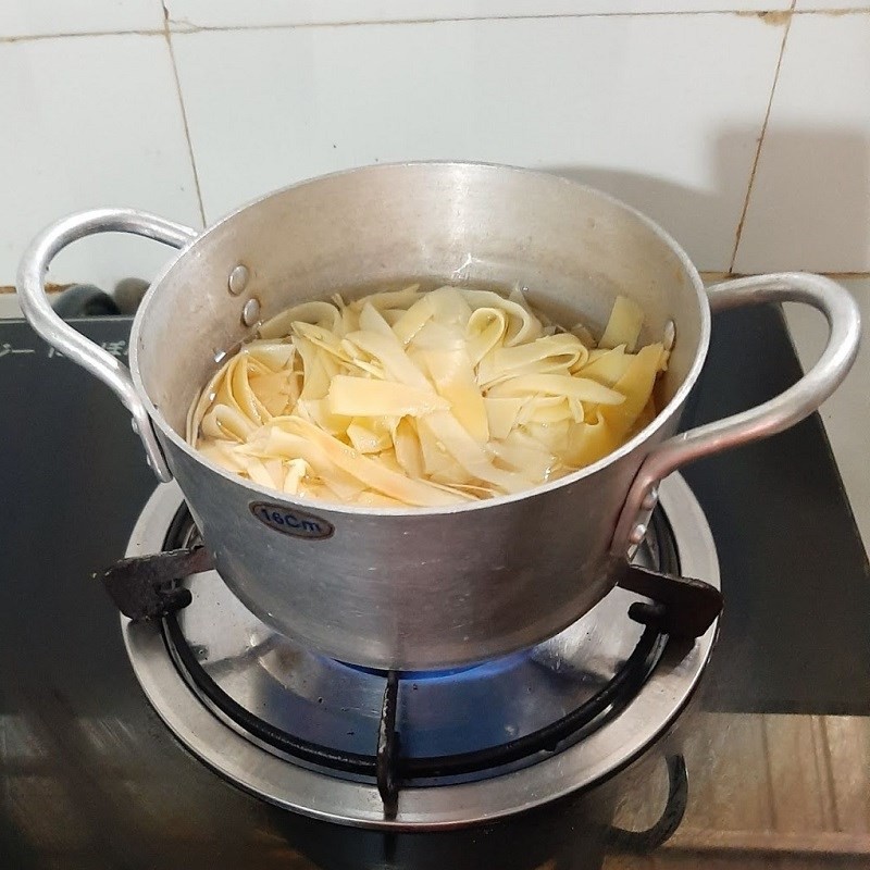 Thịt ba chỉ và măng tươi đã ướp đang được xào săn trên bếp với lửa lớn
