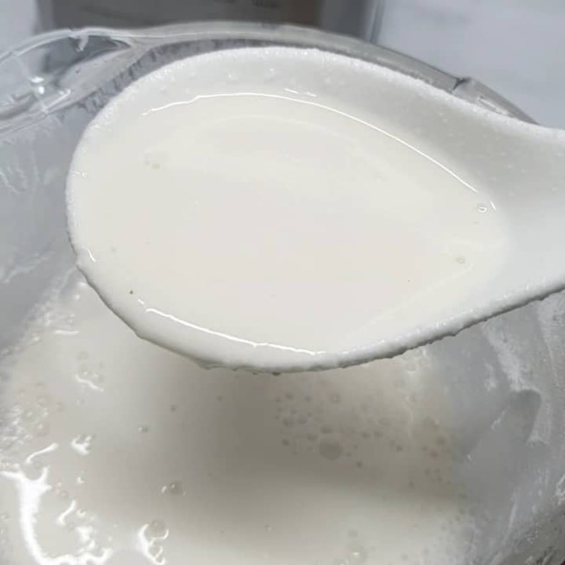 Hình ảnh sữa hạt điều hạnh nhân đang được rót ra từ máy làm sữa hạt vào chai thủy tinh