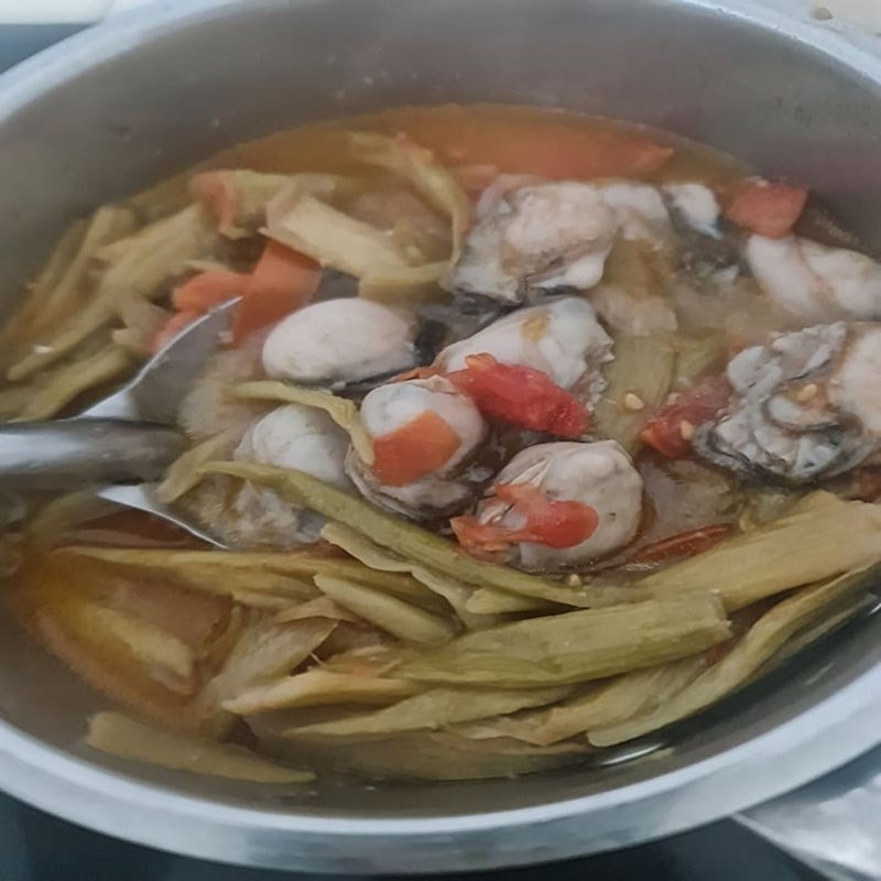 Nồi canh hàu mùng đang sôi nhẹ, dọc mùng và cà chua tạo nên màu sắc hấp dẫn