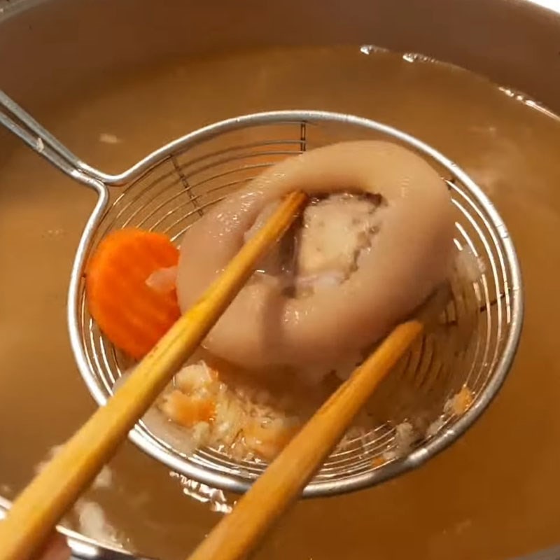 Vớt giò heo đã hầm mềm ra khỏi nồi bánh canh