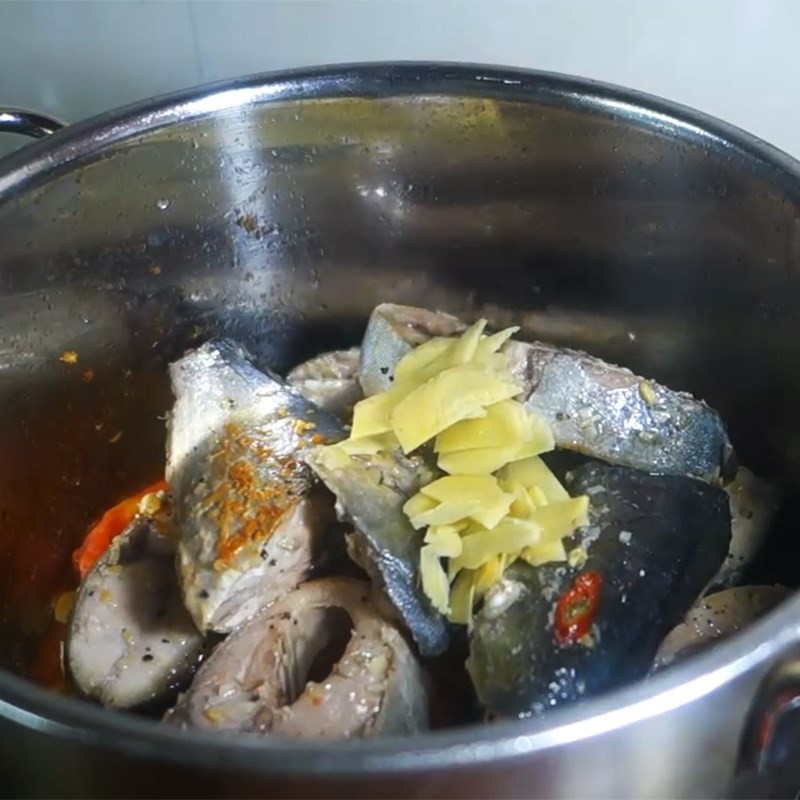 Cá cam đã chiên sơ được cho vào nồi nước dùng thơm cà chua và gừng, chuẩn bị hoàn thành món bún cá cam