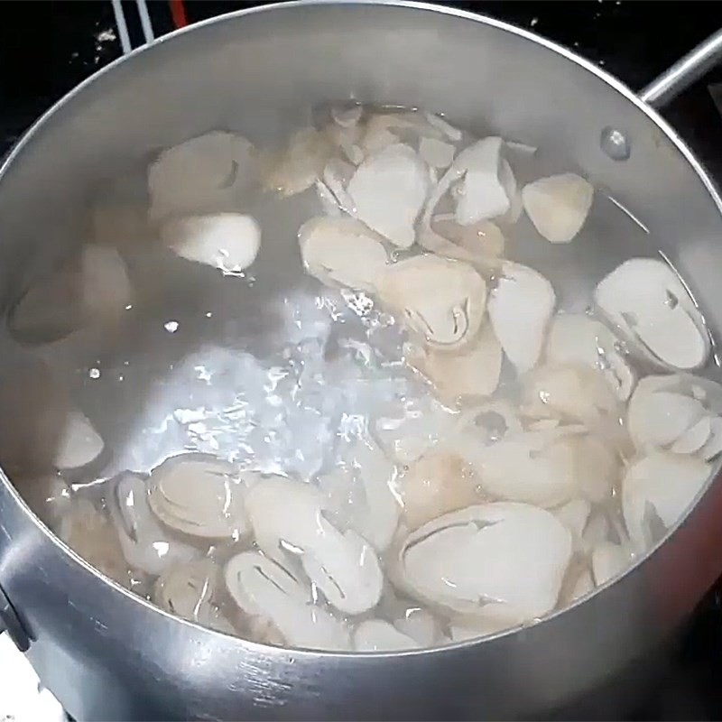 Cho nấm rơm vào nồi nước sôi, bước khởi đầu để nấu canh rau ngót nấm đậu hũ