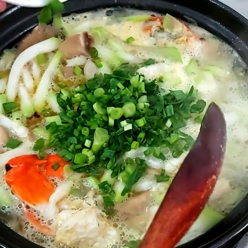Rắc hành lá thái nhỏ vào nồi canh cua nấu bầu trước khi tắt bếp