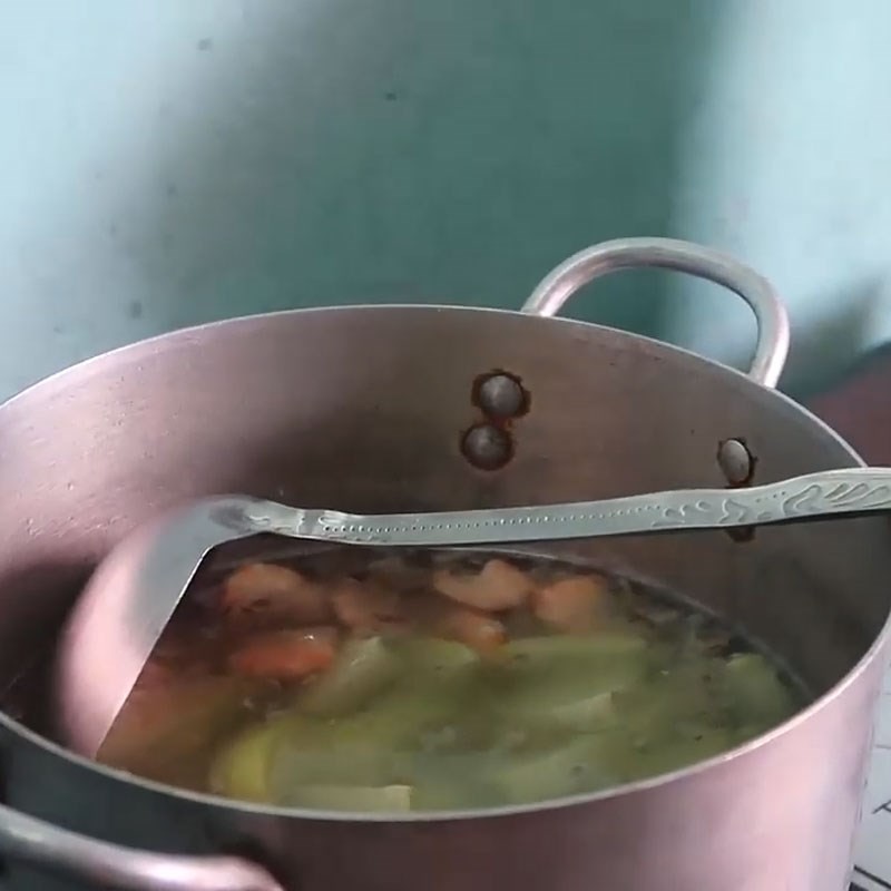 Đổ nước sôi vào nồi để bắt đầu hầm canh cá trắm dưa chua