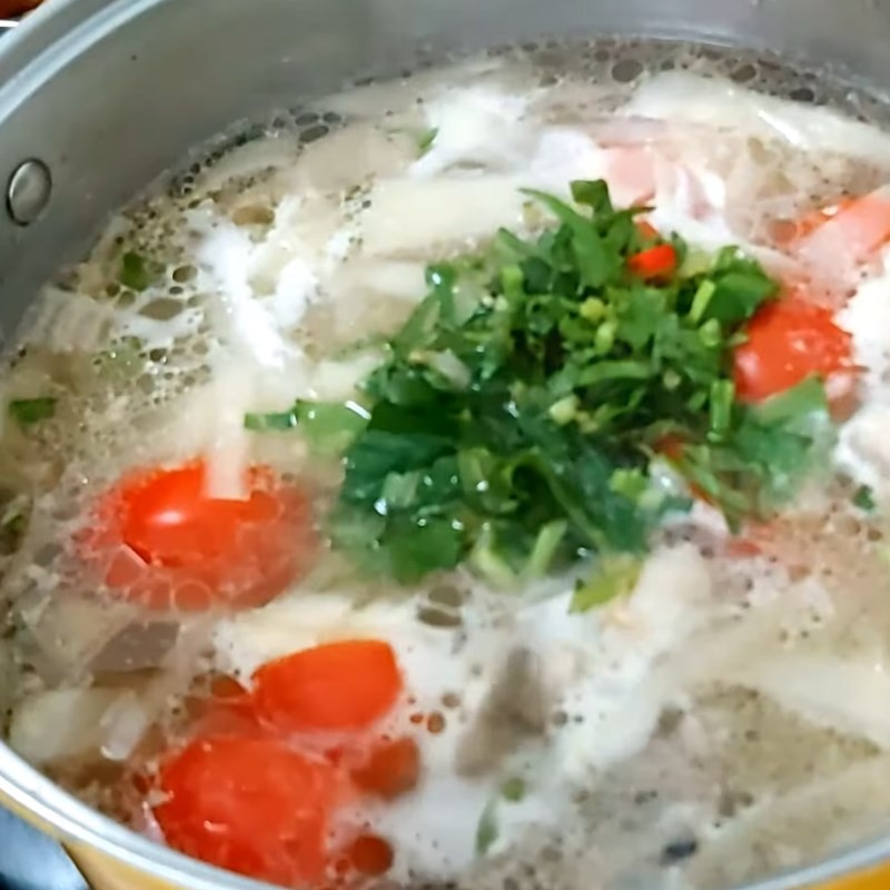 Rau thơm được thêm vào nồi canh nóng, hoàn thiện hương vị cho món canh vịt măng chua