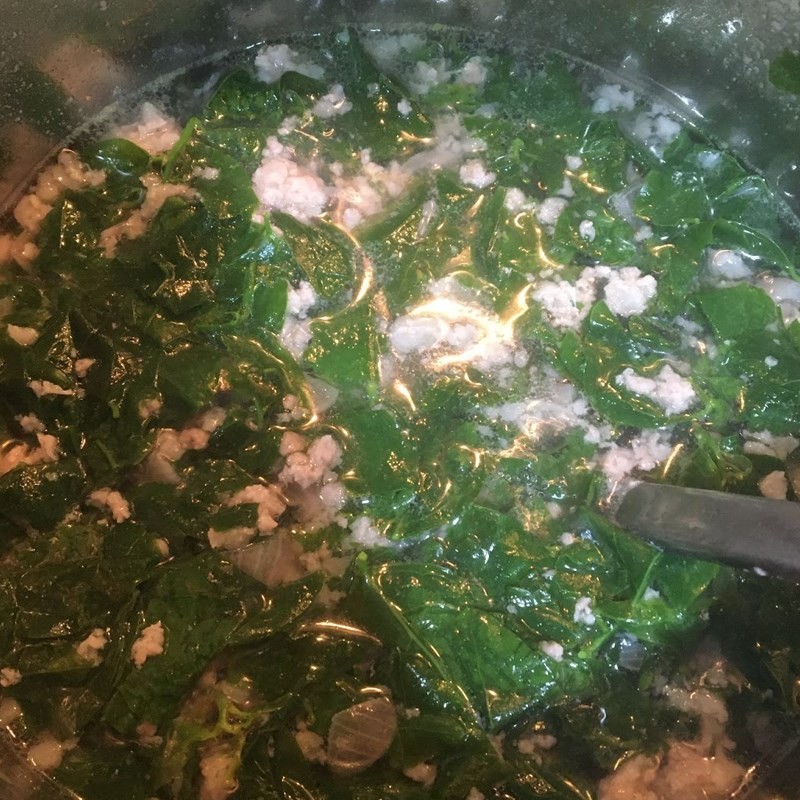 Cho hành lá và ngò rí vào nồi canh nghêu bầu trước khi tắt bếp